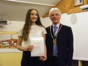 Girl in a white lace top receives her award