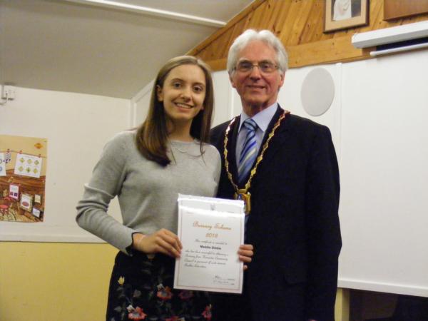 Girl in a grey sweater receives her award