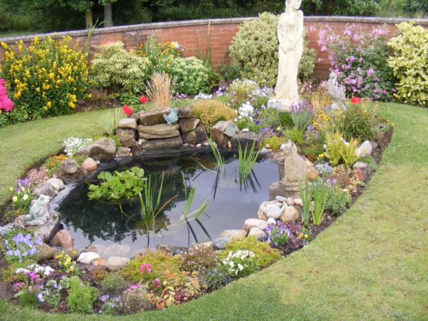 Pond with a statue, surrounded by flowers.